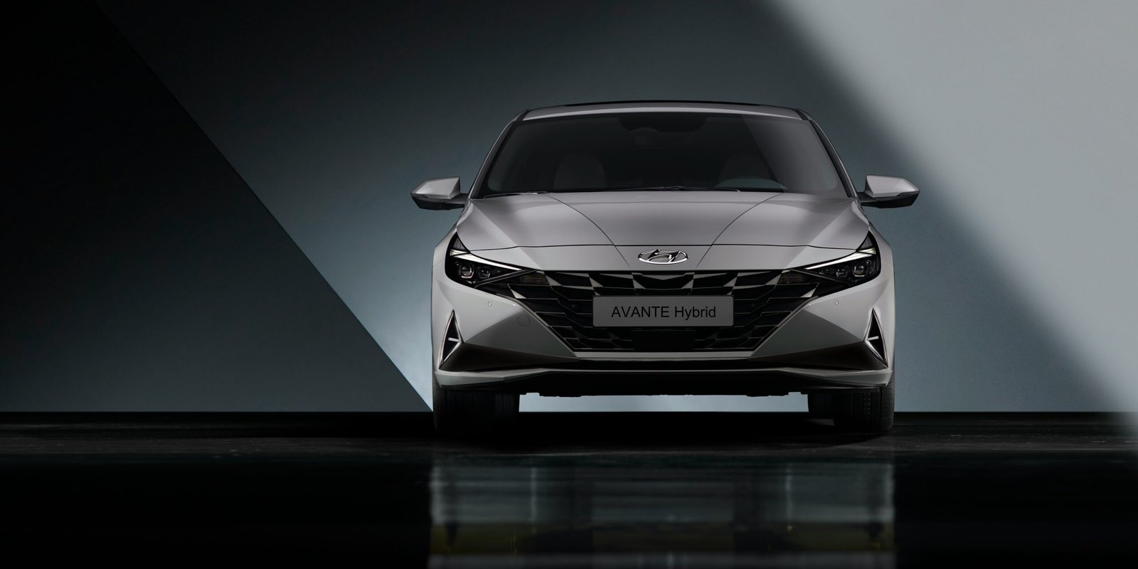 the front end of a silver car in a dark room